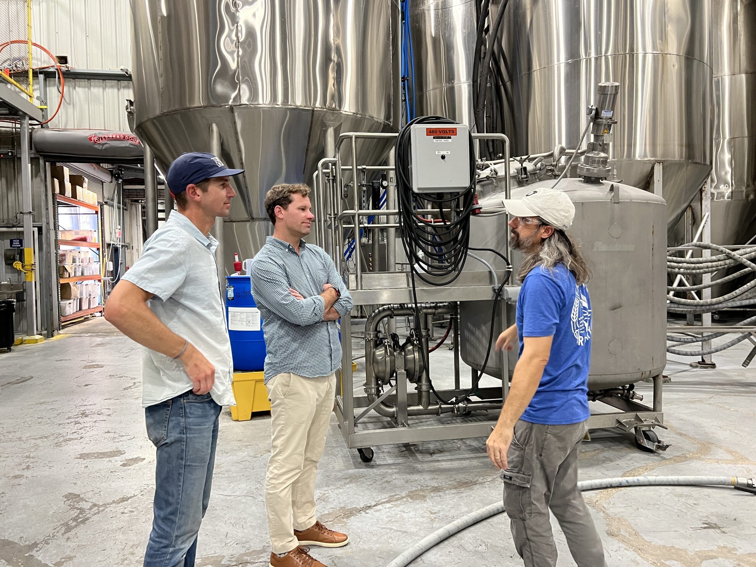 two cusomters talking with brewer in the brewhouse
