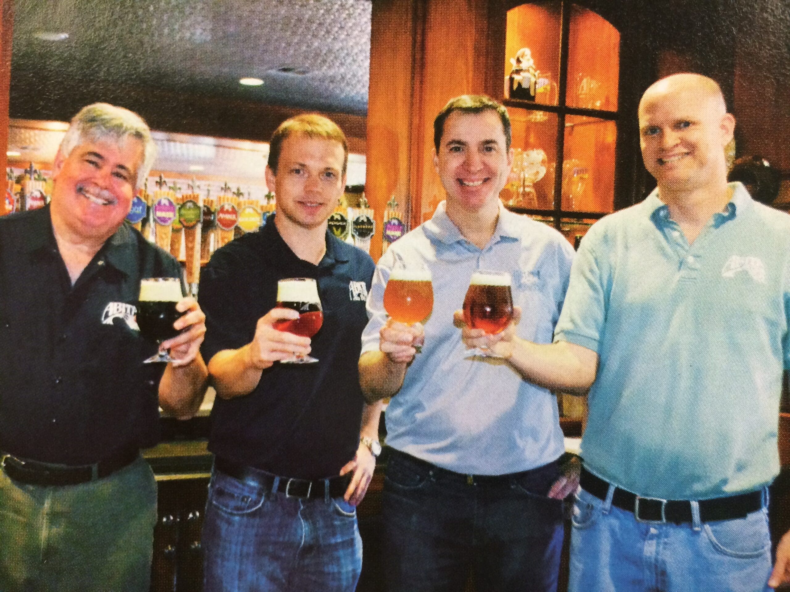 4 brewery employees toast with their beers in the abita taproom