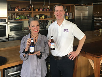 poppy tooker and dave blossman posing with beer bottles in hand