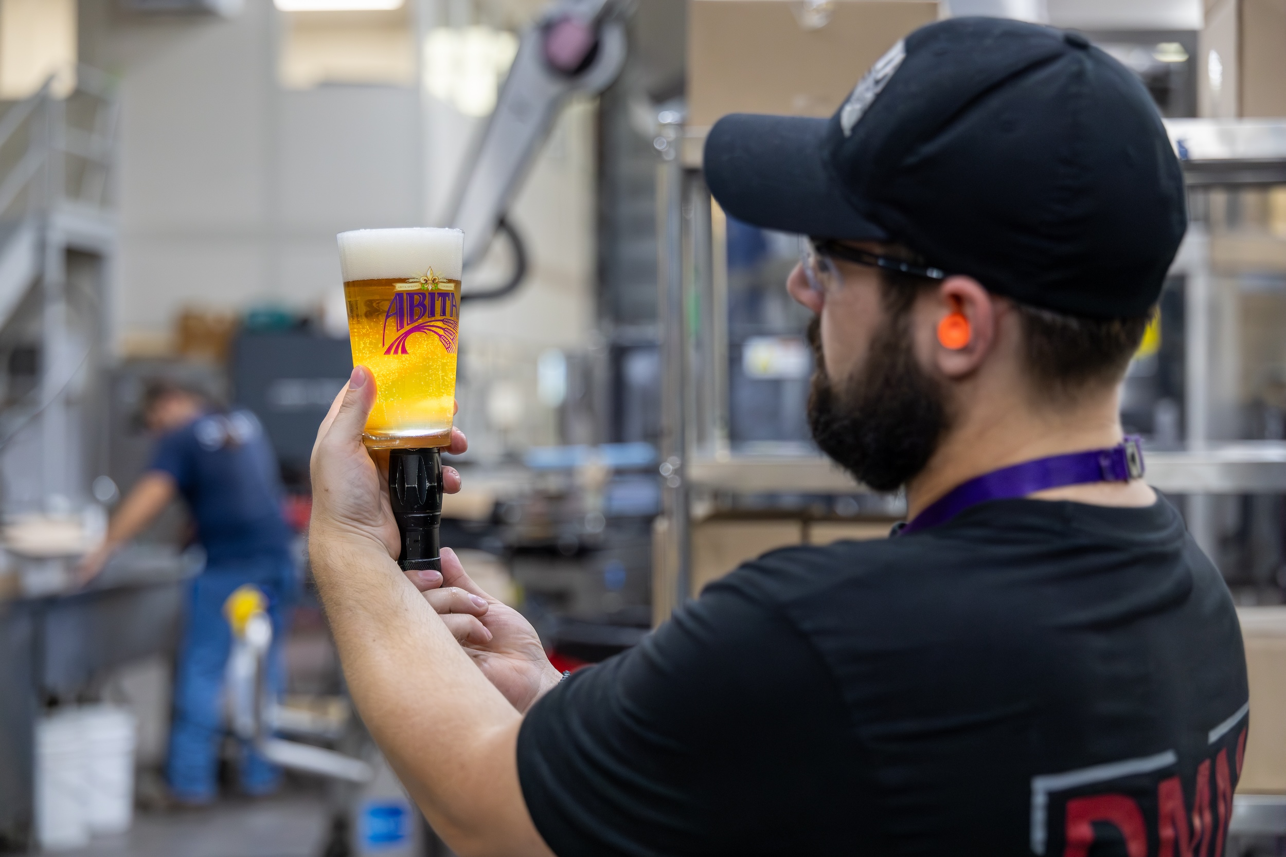 member of a beer quality control team at a cGMP certified facility looking at the cloudiness of the beer