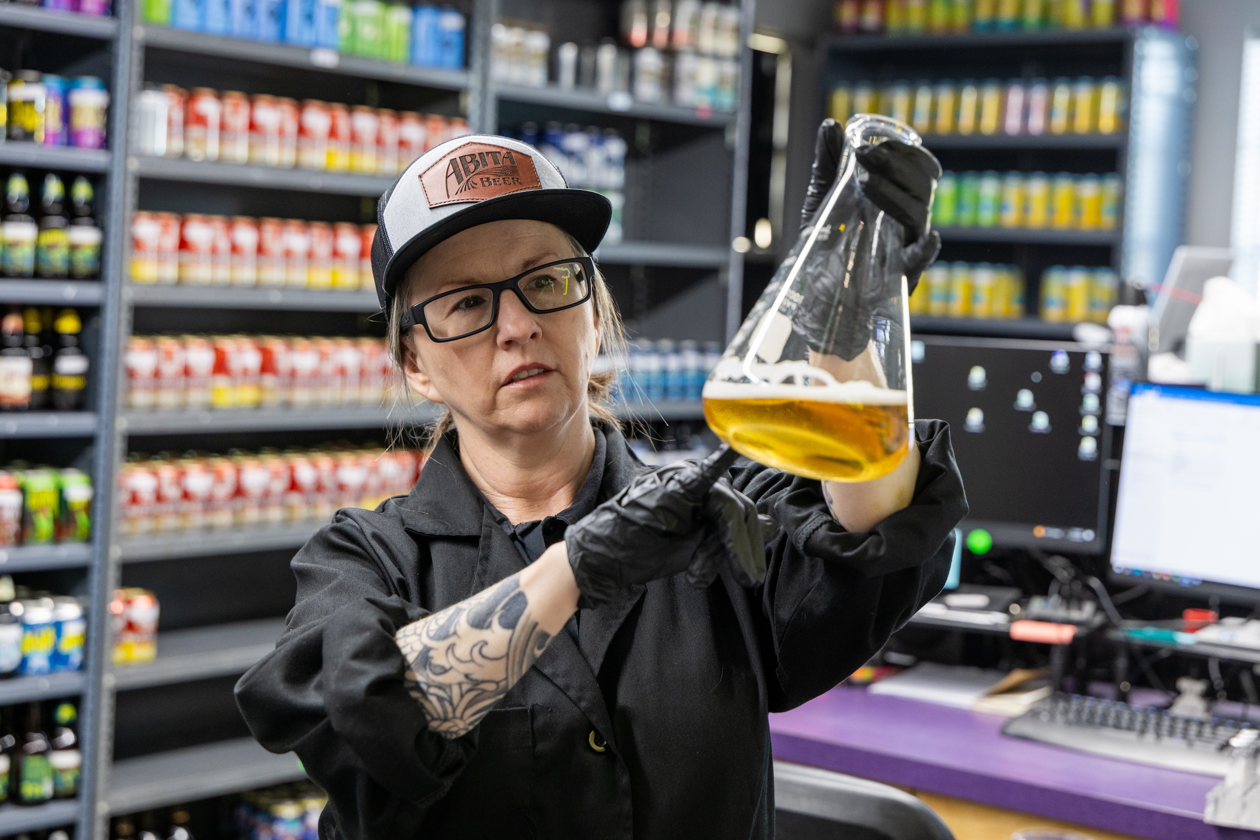 woman holding beer in a beaker in a cGMP certified beverage lab