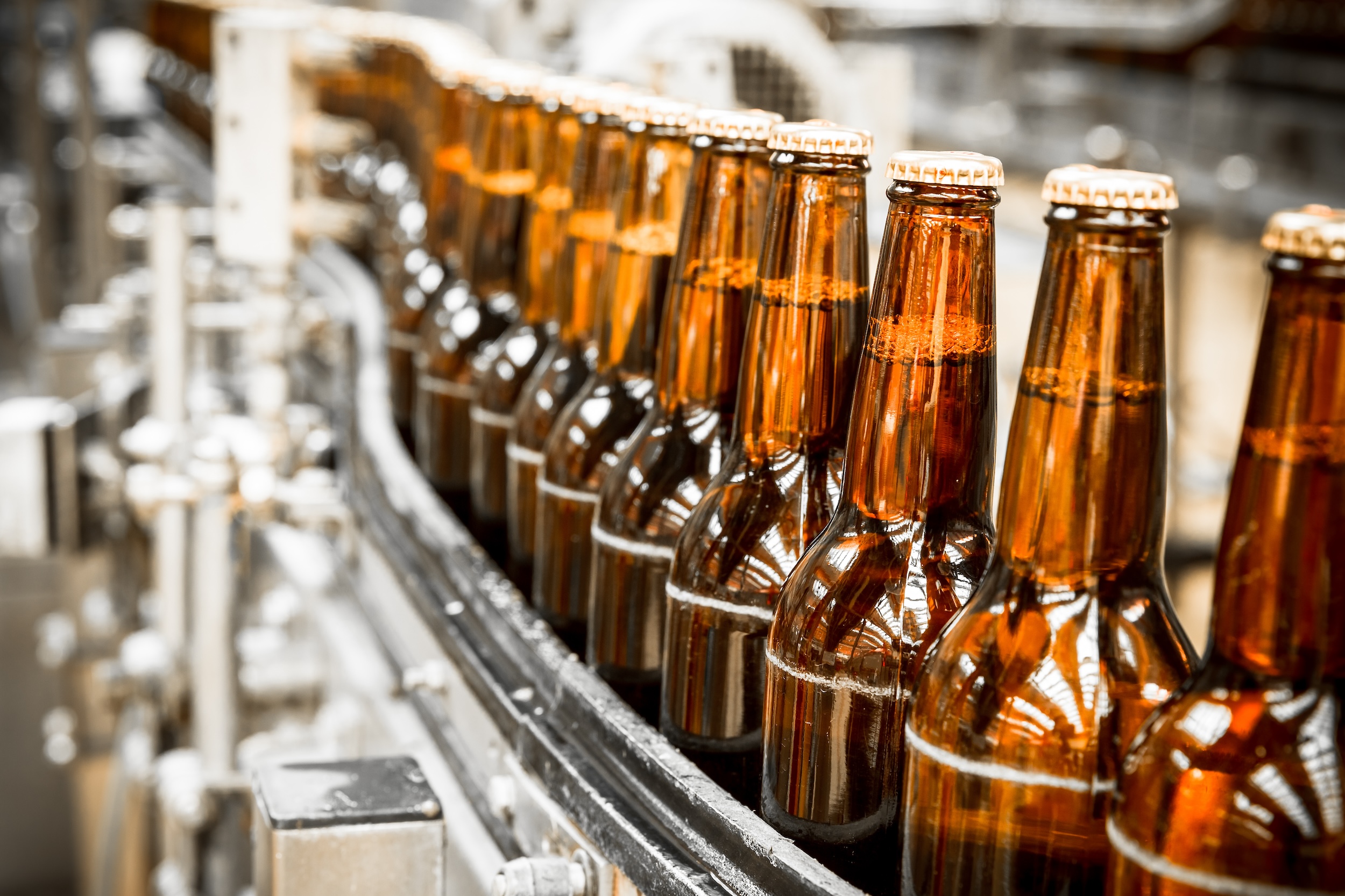 bottles of malt vs sugar beverages lined up on a conveyor belt