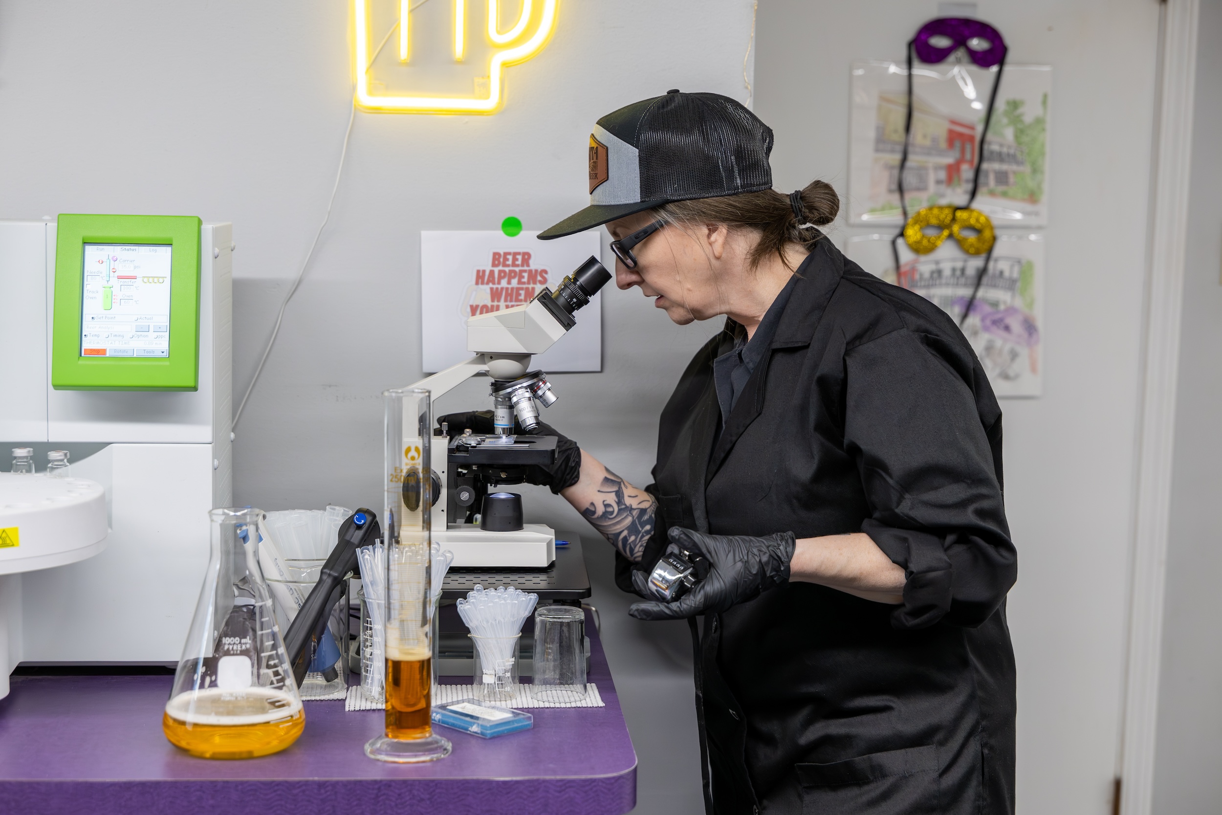 woman at a beverage quality control lab looking through a microscope