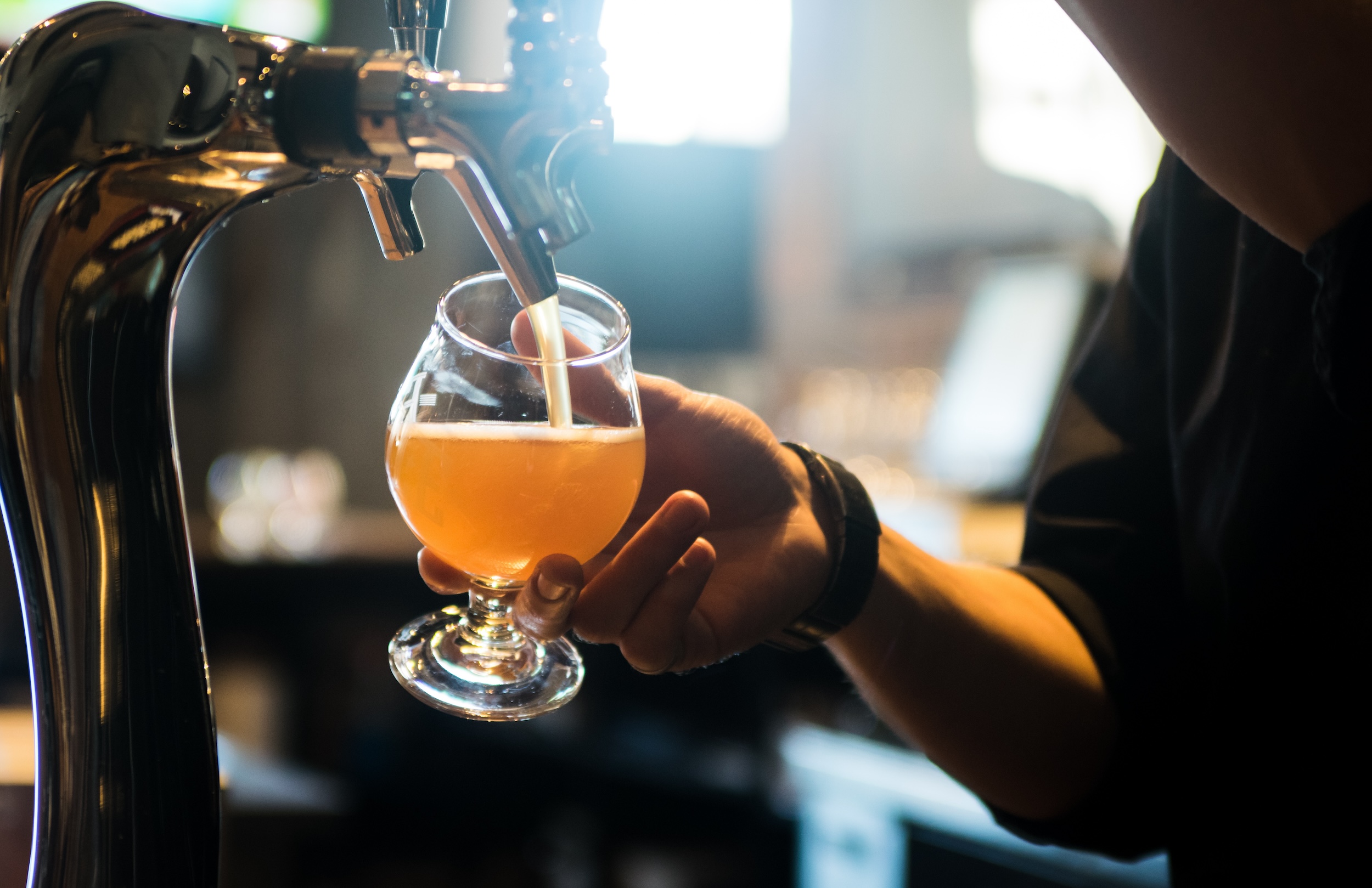 unpasteurized beer being poured into a chalice style glass from on tap