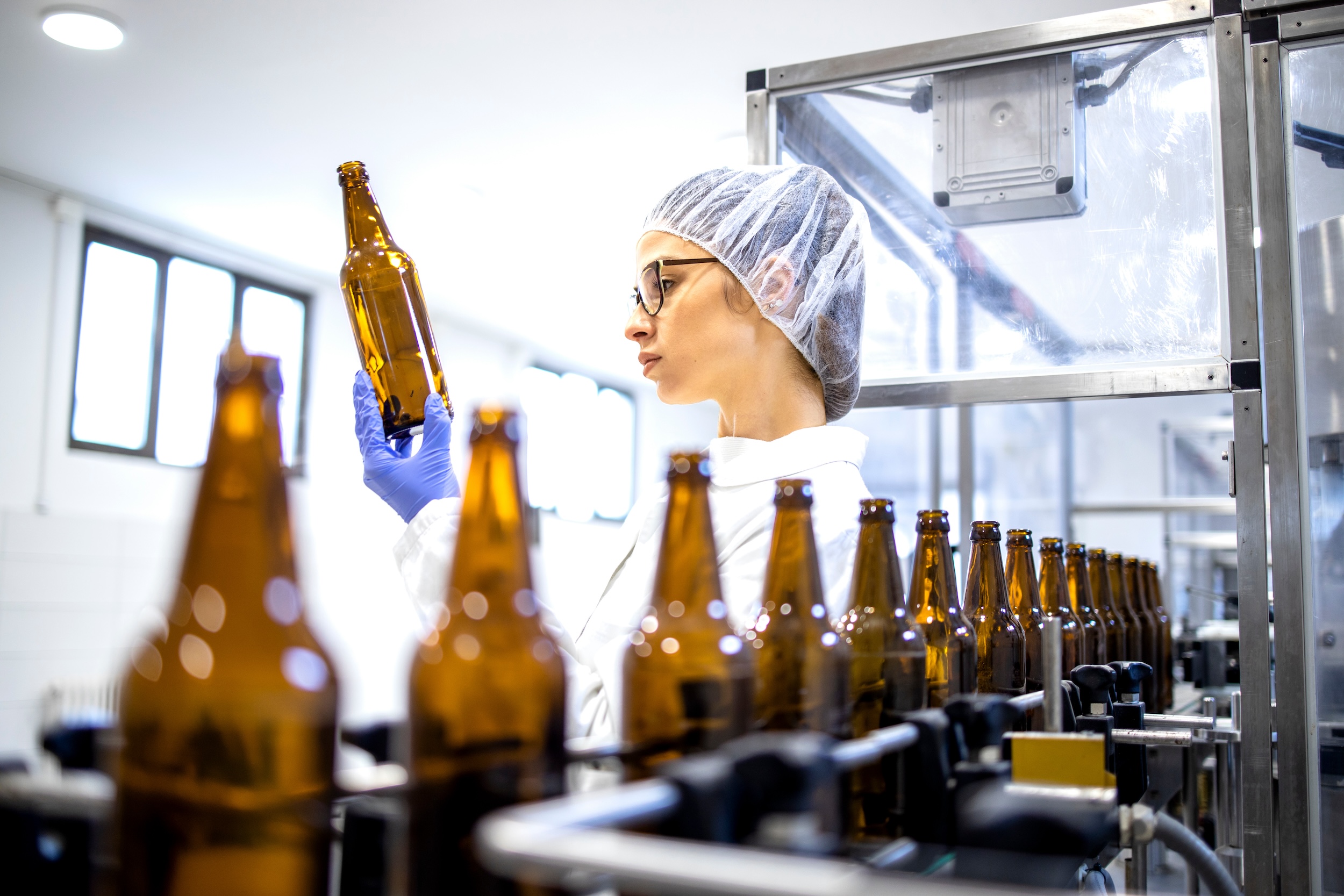 woman performing quality assurance on bottles of pasteurized beer