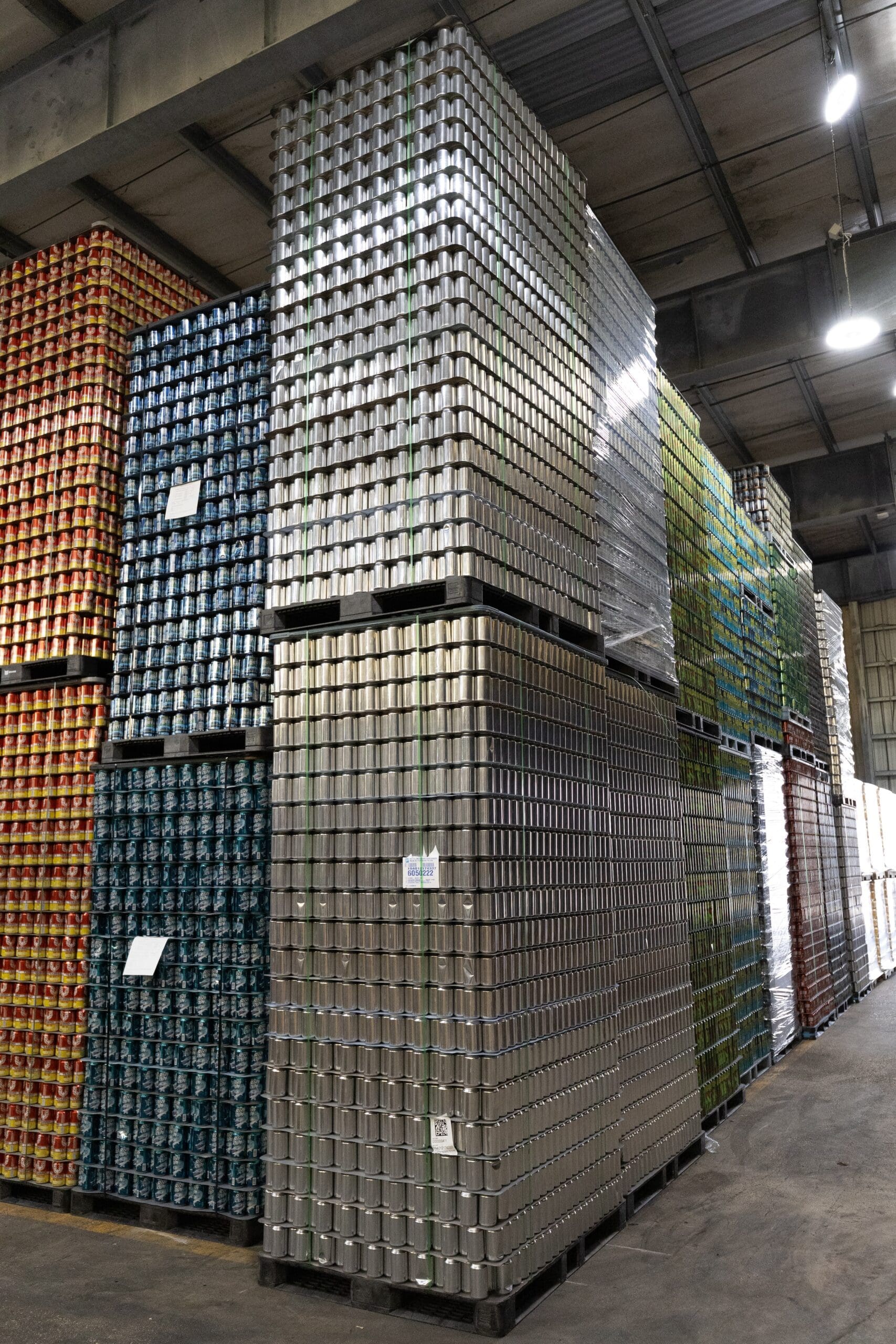 orange blue and silver cans of beer stored and stacked in a beverage warehousing management facility