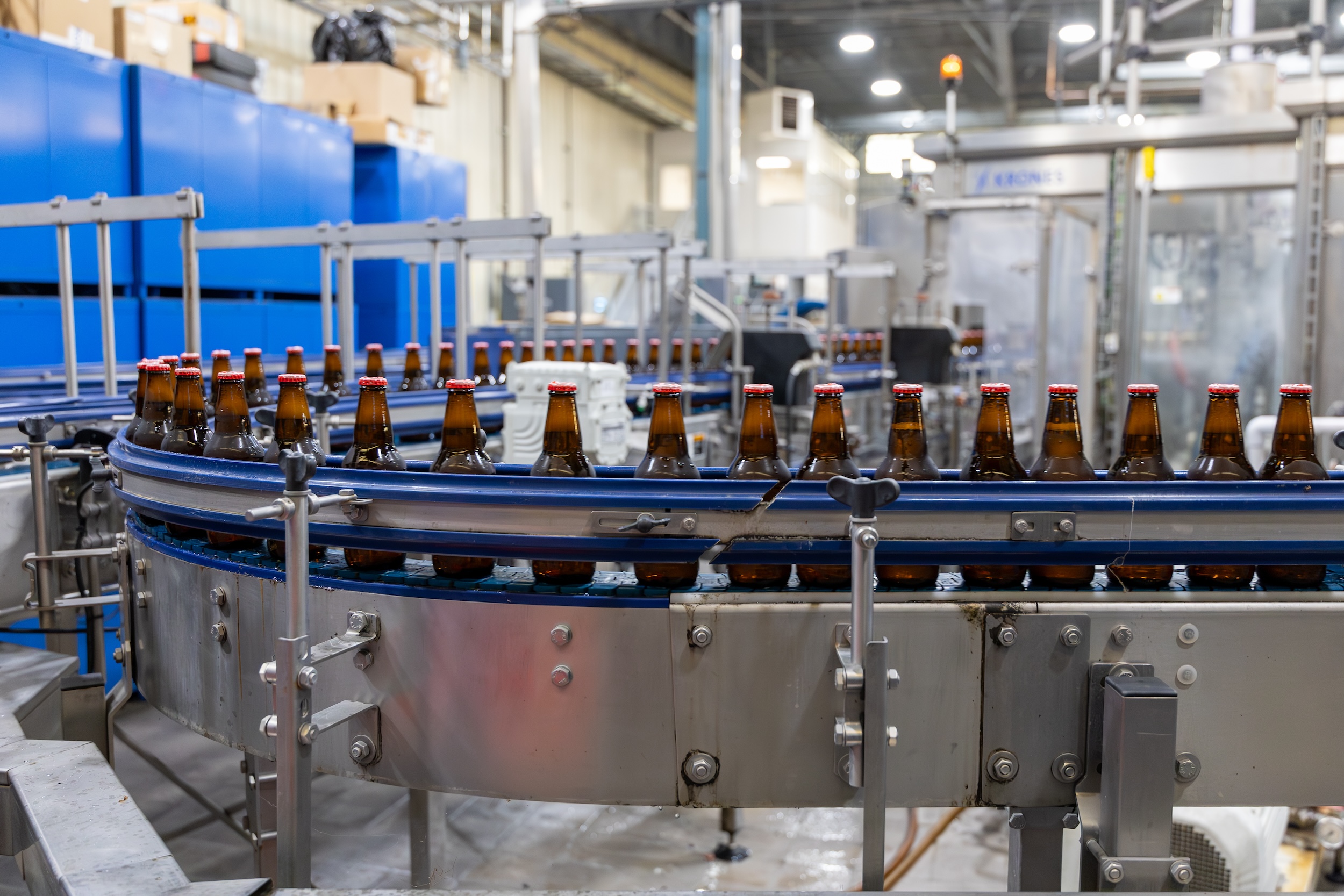 beer making its way down a conveyor belt in an open brewery manufacturing facility